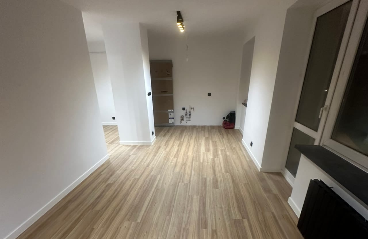 Pokój z ułożoną podłogą z paneli drewnopodobnych, widok w stronę przejścia