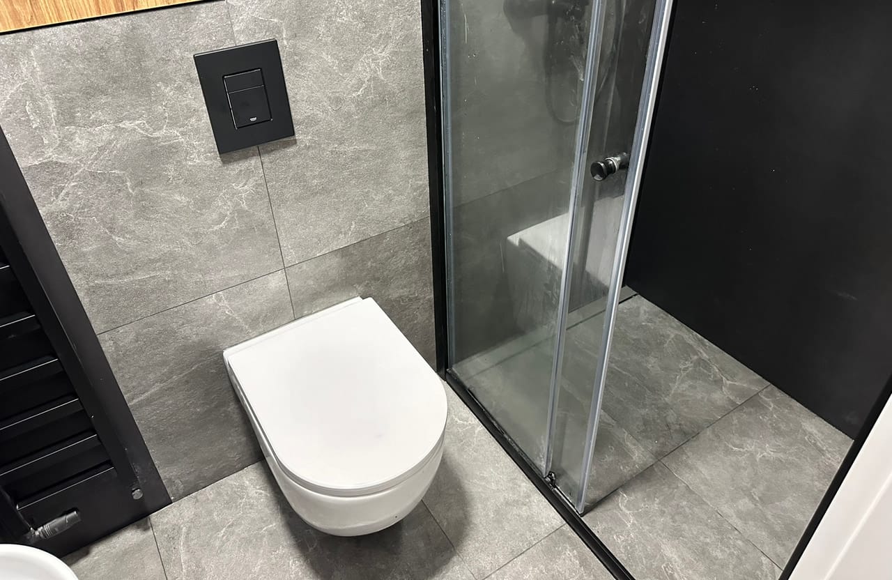 Toaleta z miską WC podwieszaną, kabiną prysznicową i podłogą drewnopodobną