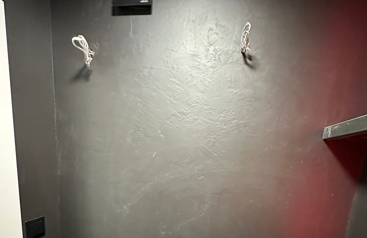 Ciemna ściana łazienki z niewielką umywalką narożną