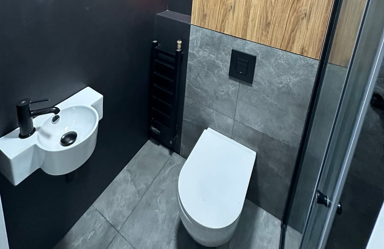 Toaleta z umywalką i miską WC podwieszaną, ściana wykończona drewnem
