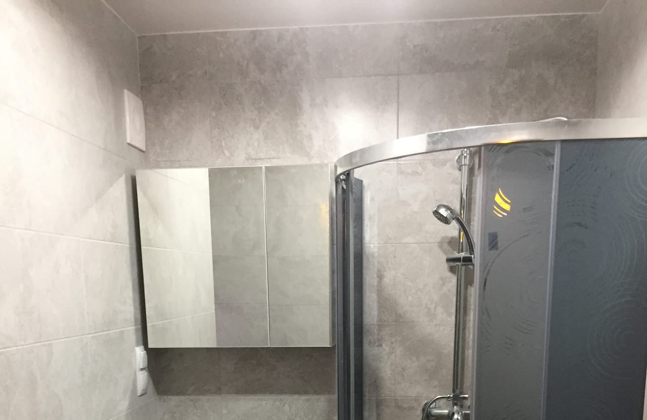Łazienka z półokrągłą kabiną prysznicową, umywalką z szafką i lustrem