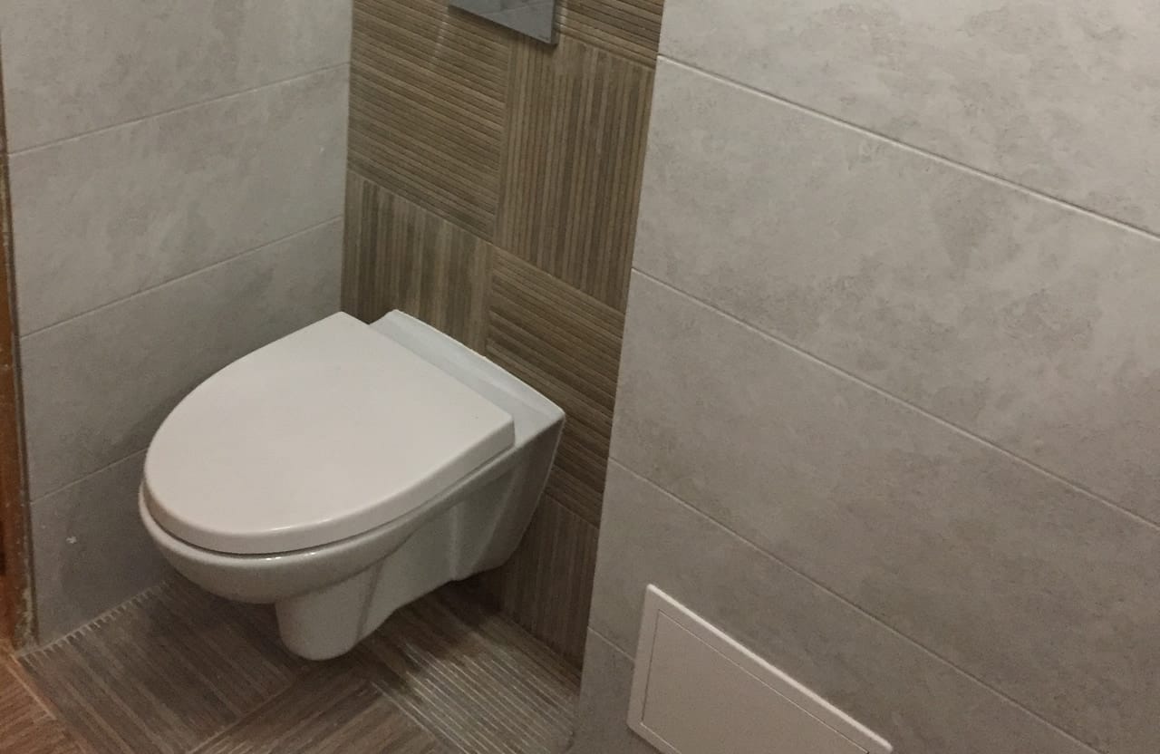 Miska WC podwieszana przy ścianie z płytek betonopodobnych i drewnopodobnych